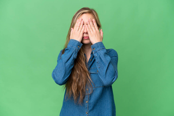 Giovane donna bionda su sfondo isolato che copre gli occhi dalle mani
 - Foto, immagini