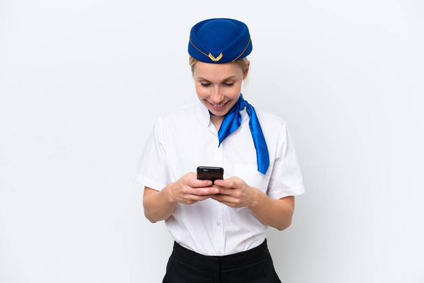 Самолет блондинка стюардесса женщина изолирована на белом фоне отправки сообщения с мобильного телефона - Фото, изображение