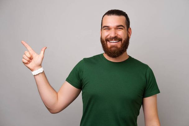 Un homme barbu souriant portant du vert pointe de côté l'espace de copie pour votre texte. - Photo, image