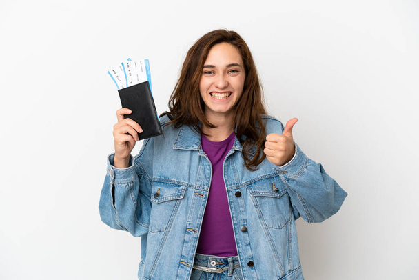 Young caucasian woman isolated on white background in vacation holding a passport and plane with thumb up - Foto, immagini