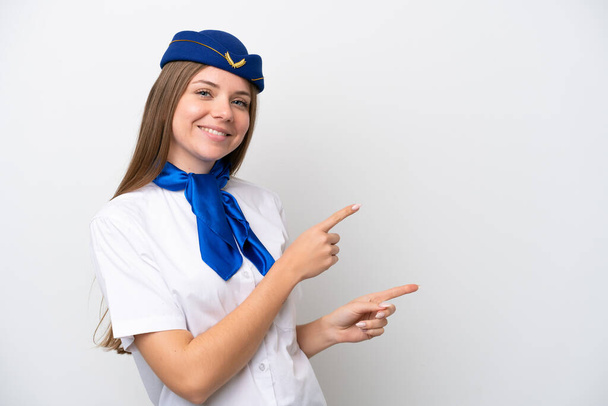 Lentokone Liettua nainen lentoemäntä eristetty valkoisella taustalla osoittaa sormella sivulle ja esittää tuotteen - Valokuva, kuva