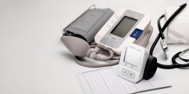 Tonometer, Brachial- und automatisches digitales Blutdruckmessgerät für das Handgelenk, Stethoskop, auf dem Tisch liegend, Druckdiagnostik, auf weißem Hintergrund, Banner, Platz für Text - Foto, Bild