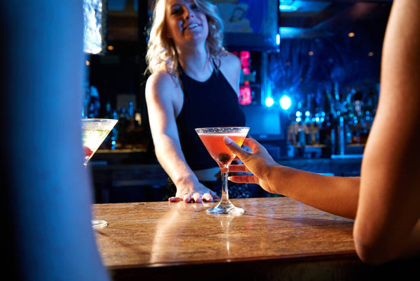 Barman, noční klub a koktejlový drink se mixologem u pultu, kde se podává alkohol v restauraci, baru nebo na novoroční párty. Ruka ženy na sklo pro pití, oslavu a servis. - Fotografie, Obrázek