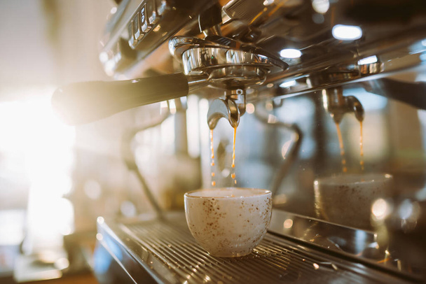 Espresso pouring from coffee machine into coffee cup. - Foto, Bild