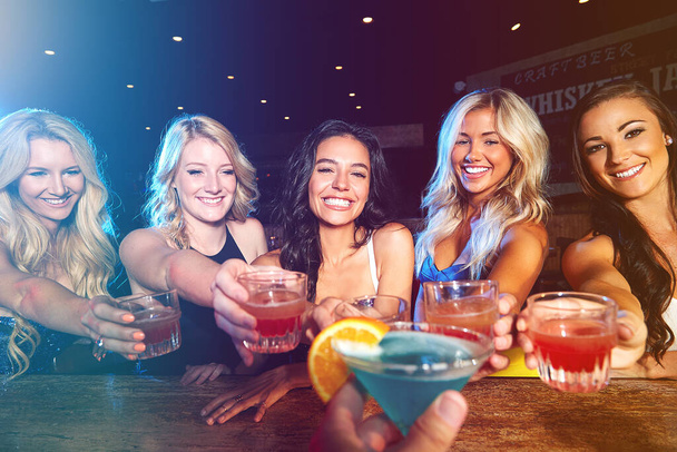 Cocktails, happy hour and friends at club with a toast to celebrate, new years social and drinks during a girls night. Party, alcohol and group of women with a cheers during a celebration at an event. - 写真・画像