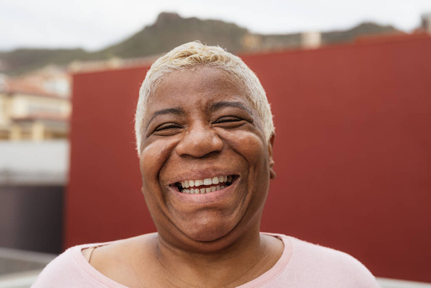 Ευτυχισμένη Λατίνα ηλικιωμένη γυναίκα που διασκεδάζει χαμογελώντας μπροστά στην κάμερα στην αυλή του σπιτιού της - Φωτογραφία, εικόνα