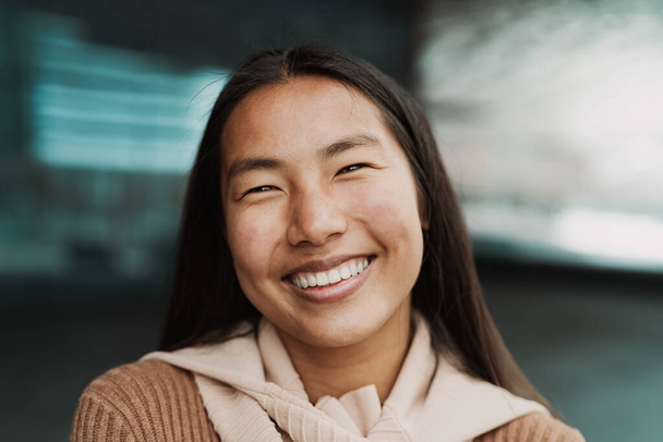 Счастливая азиатская девушка весело позирует и улыбается перед камерой - Фото, изображение