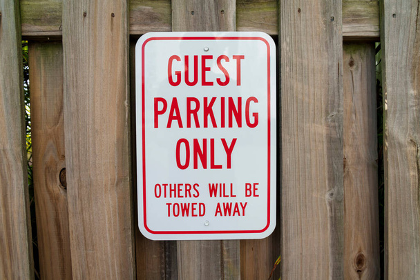 Přihlásit se na dřevěný plot s Guest Parking Only Other Will Be Towed Away- Miami, Florida. Zblízka bílá cedule s červenými rámečky a písmeny u plotu z hnědého dřeva. - Fotografie, Obrázek