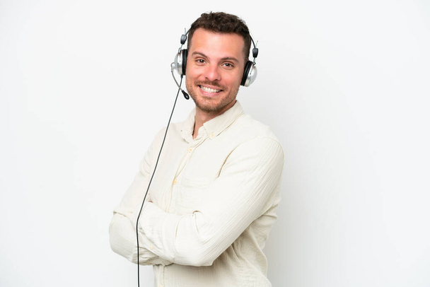 Telemarketer caucasian man working with a headset isolated on white background with arms crossed and looking forward - Foto, imagen