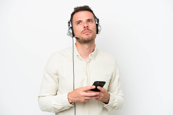 Telemarketer kaukasischen Mann arbeitet mit einem Headset isoliert auf weißem Hintergrund halten ein Gespräch mit dem Mobiltelefon - Foto, Bild