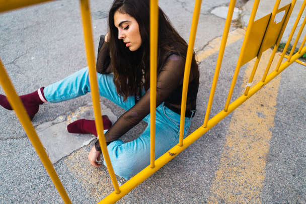 High angle shot of a young model posing for camera sitting a streets floor - Fotoğraf, Görsel