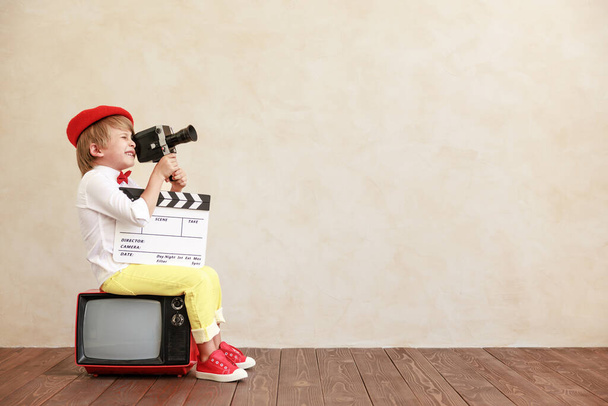 Newsboy shouting against grunge wall background. Boy selling fake news. Child wearing vintage costume. Kid holding newspaper. Social media and Internet nerwork concept - Photo, image