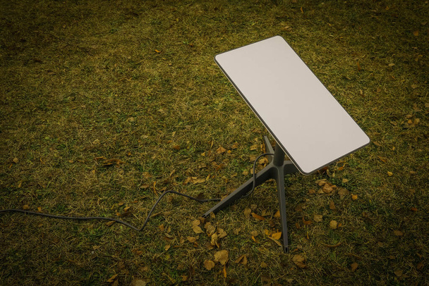 Uzaydan gelen internet sinyalini almak için bir anten. Parktaki yerdeki Starlink. - Fotoğraf, Görsel