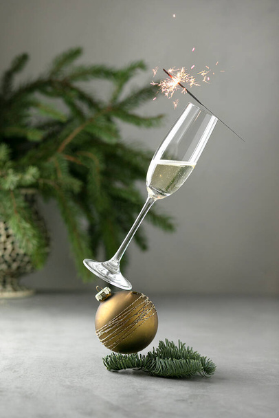 Egyensúly élelmiszer levitáció koncepcionális kreatív csendélet. Levitációs pezsgő. Egyensúlyban üveg pezsgő és karácsonyi labda szürke alapon. Újévi koncepció - Fotó, kép