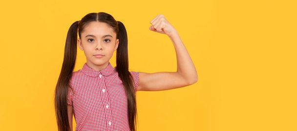 Serious girl child show power gesture flexing arm yellow background, strong. Child face, horizontal poster, teenager girl isolated portrait, banner with copy space - Photo, Image