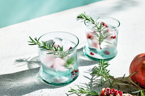 Granatapfel Gin Fizz Cocktail mit Sekt, Rosmarin und Eis. Feiertage erfrischendes alkoholisches Getränk. Kaltes Entgiftungsgetränk aus Granatapfel. - Foto, Bild