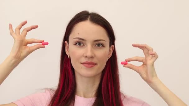 Νεαρή όμορφη γυναίκα βάζει ωτοασπίδες στα αυτιά της, προστασία από το θόρυβο - Πλάνα, βίντεο