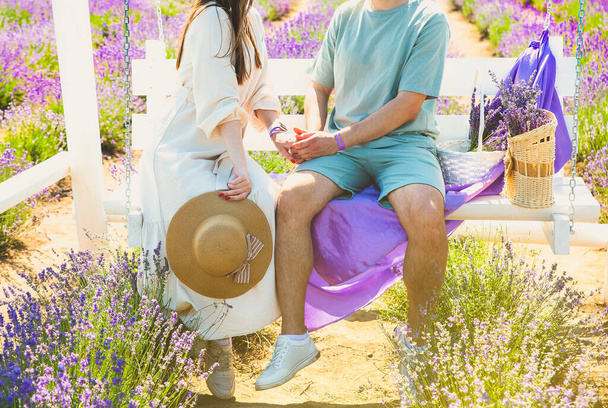 Een paar knuffels op een witte houten bank, romantisch liefdesverhaal. Prachtige paarse lavendelbloemen op het zomerveld. Warm en inspirerend concept. - Foto, afbeelding