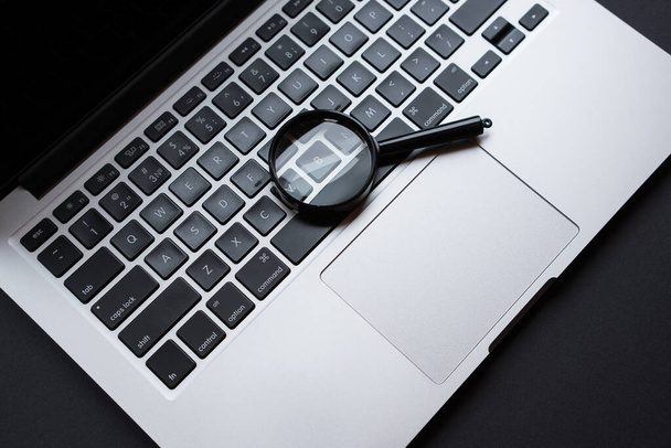 Laptop com lupa, em mesa de escritório escuro, conceito de pesquisa. - Foto, Imagem