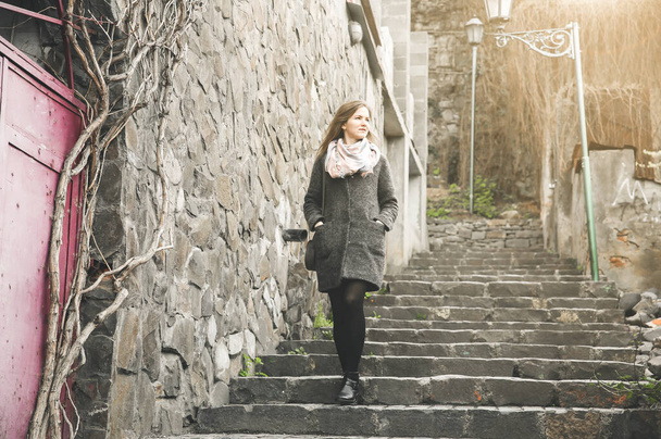 Κορίτσι είναι το περπάτημα στο στενό δρόμο με πέτρινο πεζοδρόμιο. Κομψή γυναίκα. Μεσαιωνικό φανάρι. Σκάλες στην πόλη. - Φωτογραφία, εικόνα