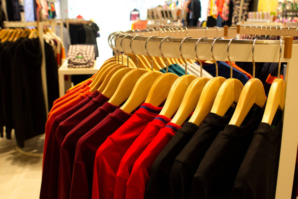 Camisa y pantalón colgando de perchas en un estante de ropa y dispuestos en un estante en una tienda de ropa moderna - Foto, Imagen