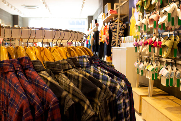 Camisa y pantalón colgando de perchas en un estante de ropa y dispuestos en un estante en una tienda de ropa moderna - Foto, imagen