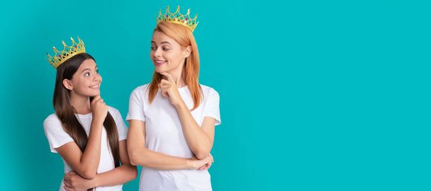 Mother and daughter child banner, copy space, isolated background. Arrogant woman mother and daughter child smile at each other wearing crowns blue background, selfish - Photo, Image