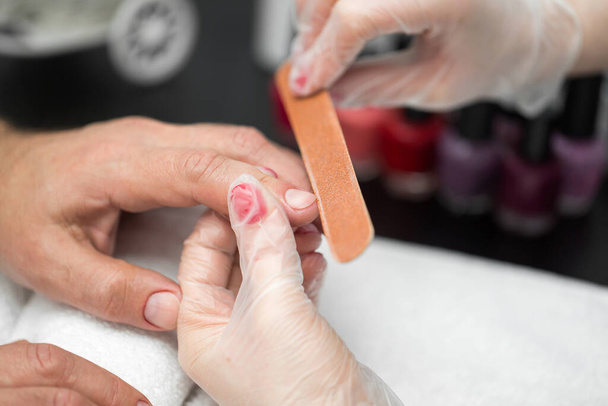 Girl manicurist doing manicure for man in beauty salon - Photo, image