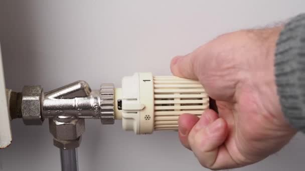 Eine Person schaltet die Heizung ein, indem sie das Thermostat des Heizkörpers auf den Maximalmodus stellt, um die Temperatur im Raum aufrecht zu erhalten. - Filmmaterial, Video