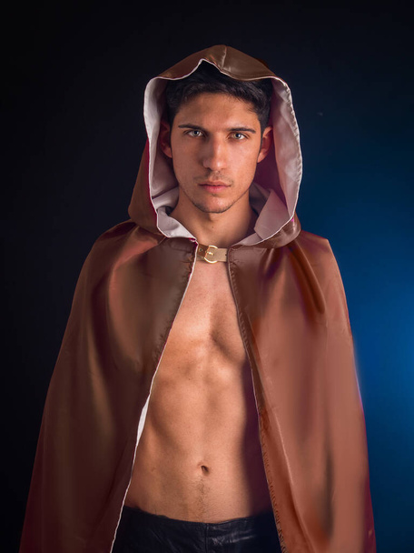 Handsome young man in old fashioned cloak on dark smoky background - Foto, afbeelding