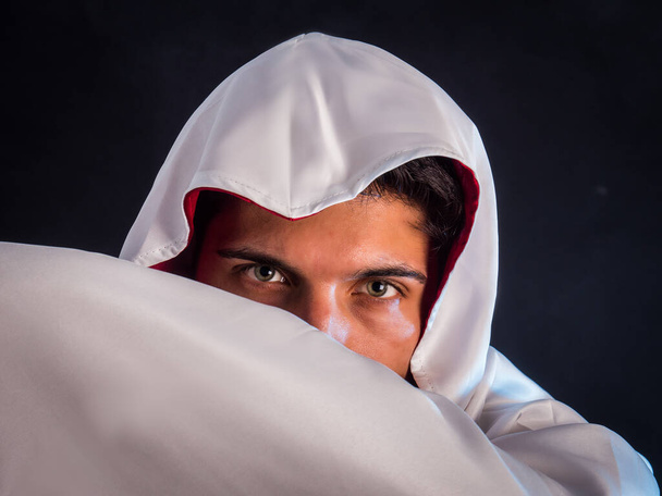 Close-up of handsome young man in old fashioned cloak on dark background - Foto, Bild