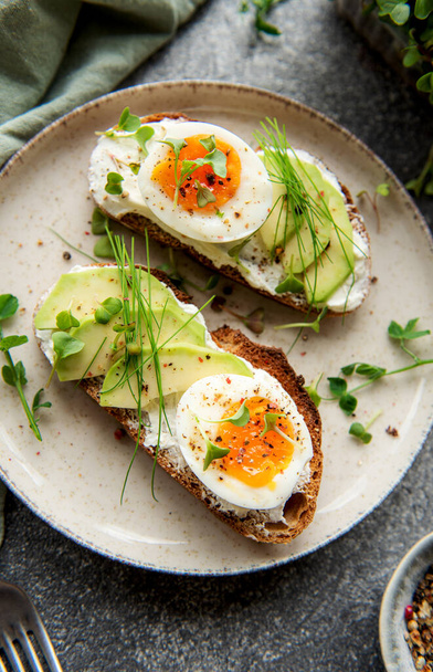 Bread toast, boiled eggs, avocado slice, microgreens on a plate, breakfast time - 写真・画像