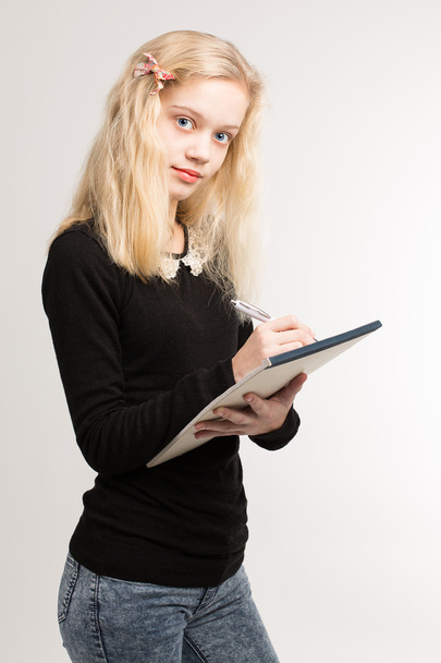 Blond Teen Girl Writing Notes on Notepad
 - Фото, изображение