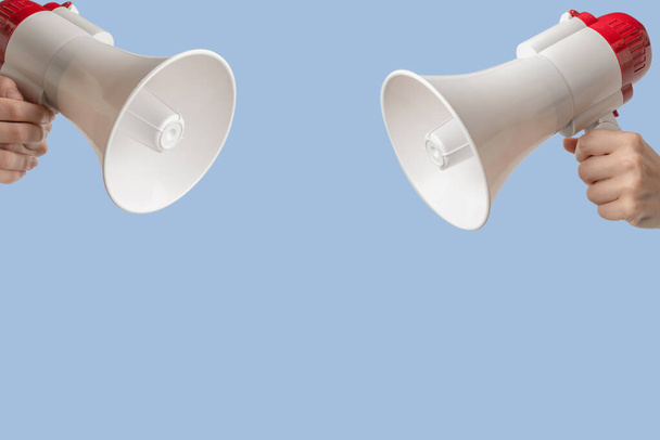 Megaphone in woman hands on a blue background.  Copy space.  - Фото, изображение