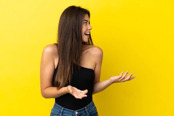 Νεαρή Βραζιλιάνα γυναίκα απομονωμένη σε κίτρινο φόντο με έκφραση έκπληξη, ενώ ψάχνει πλευρά - Φωτογραφία, εικόνα