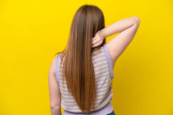 Молода біла жінка ізольована на жовтому тлі в положенні спини і мисленні
 - Фото, зображення
