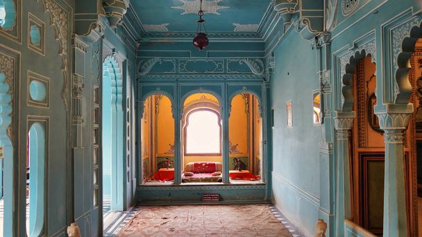 Piękne jasnoniebieskie pokoje wewnątrz pałacu miasta Udaipur. Rajasthan, Indie. Kolorowy, urządzony widok na wnętrze Pałacu Miejskiego. Wnętrze pałacowej lampy, wentylatora i ramy - Zdjęcie, obraz