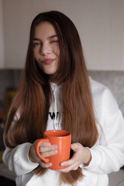 Aranyos nő függőleges portré tartó csésze otthon és kacsintás - Fotó, kép
