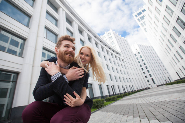 The girl hugs her boyfriend. High white buildings - Photo, image