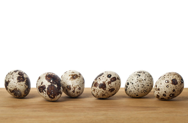 Αυγά ορτυκιού σε ξύλινο τραπέζι που απομονώνονται σε λευκό φόντο. Θέση για κείμενο. Μέγιστος χώρος αντιγραφής - Φωτογραφία, εικόνα