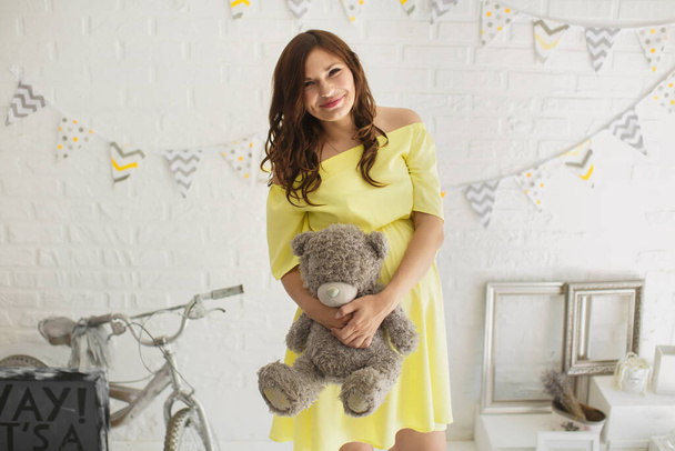 Beautiful pregnant woman in a yellow dress in the Studio - Fotó, kép