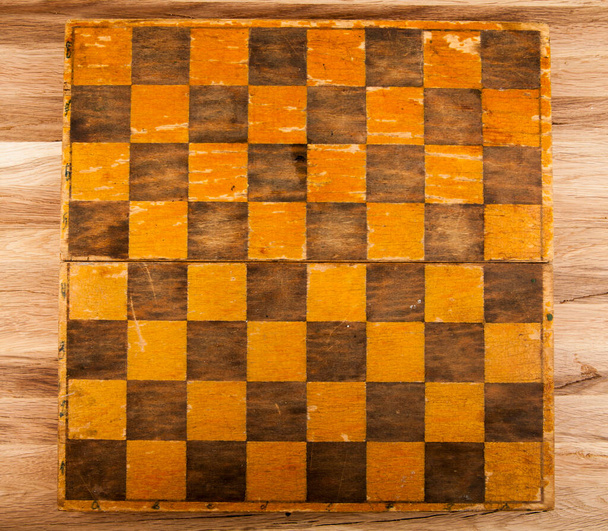 Old vintage chessboard on a wooden background. View from above. - Photo, Image