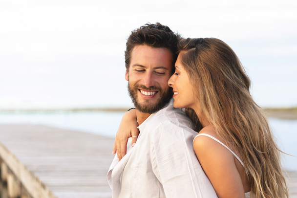woman embracing her man from behind on seaside background - Photo, Image