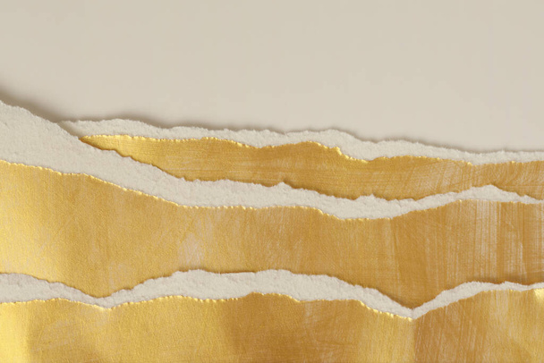 Gold torn empty pieces of texture paper on light beige copy space background. - 写真・画像