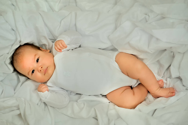 新生児の笑顔と笑い。感情を表す。赤ちゃんは白い布の上に - 写真・画像