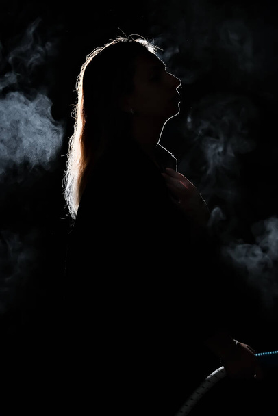silhouette of a girl in the dark. smoke . steam . girl in a dark room. - Zdjęcie, obraz