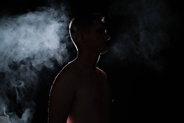 la silhouette di un ragazzo. uomini al buio. fumo. vapore. uomo in una stanza buia. - Foto, immagini