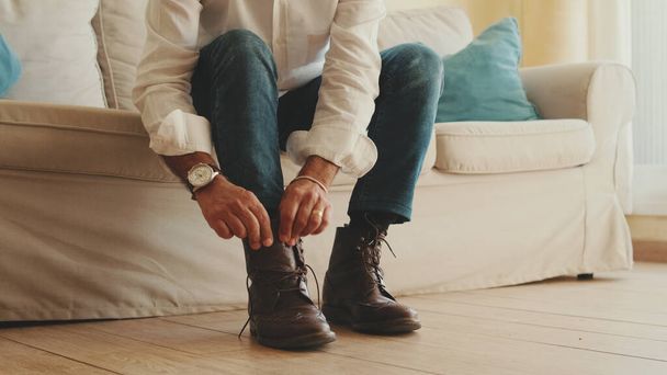 Close-up of legs of mature man putting on casual boots, tying shoelaces - Foto, immagini
