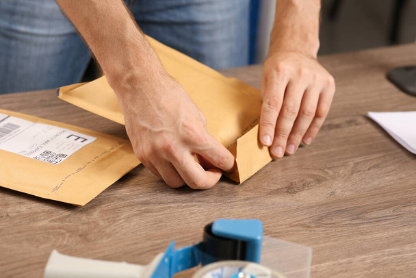 Post office worker sealing adhesive paper bag at counter indoors, closeup - Foto, imagen