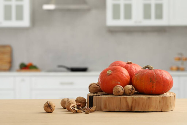 Fresh pumpkins and walnuts on wooden table in kitchen, space for text - Foto, imagen